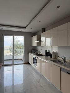 a kitchen with white cabinets and a large window at Ocean Breeze Apartment in Maputo