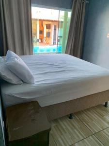 a bed with white sheets and pillows in a room at Casa Camocim Marilago in Camocim