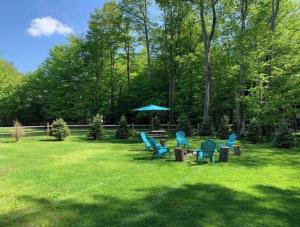 a group of chairs and an umbrella in a yard at Evergreen Villa Poconos - Hot Tub, Fire Pit, Close to Kalahari, Great Wolf Lodge and Camelback in Tobyhanna
