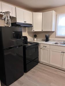 a kitchen with a black refrigerator and white cabinets at Skipper Apt 1 in Rockingham +8 photos