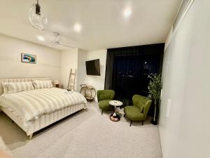 a bedroom with a bed and two green chairs at Splendid Spacious - Port Melbourne Beachside Home in Melbourne