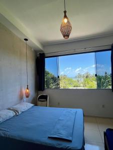 a bedroom with a blue bed and a large window at Pousada Leve Mar in Ilhéus