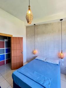 a bedroom with a blue bed and two pendant lights at Pousada Leve Mar in Ilhéus +12 photos