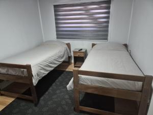 two beds in a small room with a window at Alojamiento Costanera in Laraquete