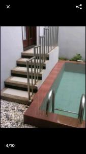 a swimming pool with stairs next to a building at Villa Oentoeng 1 Private Pool 3 Kamar in Punten