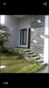 a building with a stone wall and stairs in a yard at Villa Oentoeng 1 Private Pool 3 Kamar in Punten
