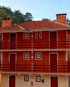 a red building with a red roof at Pousada Varanda Colibri in Monte Verde