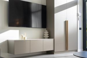 a bathroom with a white cabinet and a tv on a wall at Giruliai loft in Klaipėda