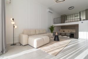 a white living room with a white couch and a rug at Giruliai loft in Klaipėda