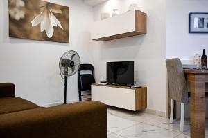 a living room with a couch and a tv and a fan at 10 Msida Park Residence in Msida