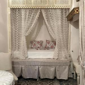 a canopy bed with curtains in a bedroom at Dar EMNA in Kairouan