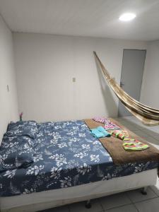a bedroom with a bed with a blue blanket and slippers at Pousada Ouro branco Mossoró RN in Mossoró