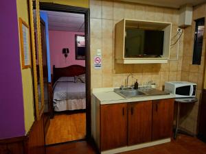 a kitchen with a sink and a microwave and a bedroom at Hotel La Castellana in Santiago +60 photos