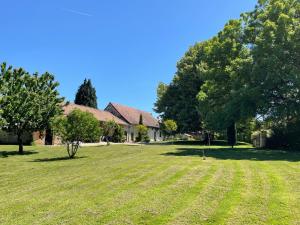 a large yard with trees and a house at Lime Tree Farmhouse in Saint-Saud-Lacoussière