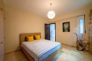 a bedroom with a bed with yellow pillows and a chandelier at The Captain's View in Aegina