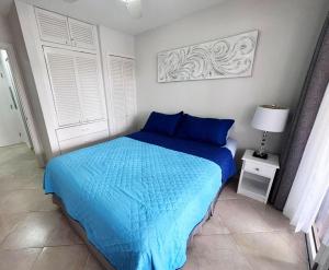 a bedroom with a bed with blue sheets and a window at Lantana 8 in Saint James +3 photos