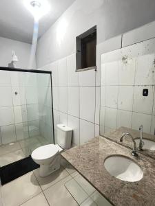 a white bathroom with a toilet and a sink at Pousada Leve Mar in Ilhéus