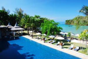 a swimming pool with lounge chairs and the ocean at Nakamanda Resort and Spa- SHA Plus in Klong Muang Beach