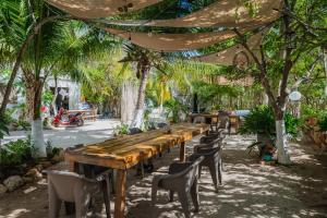 a long wooden table and chairs in a garden at Camping, Glamping y Caravanas Dos Lunas in Celestún