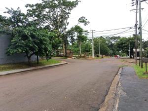 an empty street with a tree and a building at jazmin apart iguazu in Puerto Iguazú