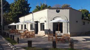 a group of tables with umbrellas in front of a building at Hosteria Alto Alegre in Coronel Moldes
