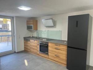 a kitchen with a black refrigerator and wooden cabinets at Gästehaus Wain I Monteur- & Ferienwohnung für 5 I 2 SZ I Terrasse I Parkplatz I WLAN in Wain
