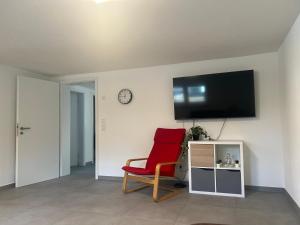 a living room with a red chair and a flat screen tv at Gästehaus Wain I Monteur- & Ferienwohnung für 5 I 2 SZ I Terrasse I Parkplatz I WLAN in Wain +6 photos