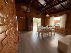a dining room with a table and chairs and a brick wall at Gastehaus Watzko in Piçarras