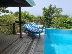 two blue chairs sitting on a deck next to a swimming pool at Beautiful Cottage overlooking Sea in Goodwood