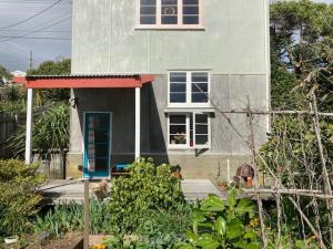 a house with a cat sitting in front of it at Self-contained studio by the beach in Paekakariki