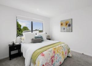 a white bedroom with a large bed and a window at Unique Stays in Auckland
