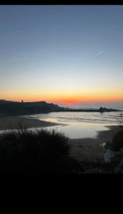 a sunset over a beach with the ocean at An Treth in Bude