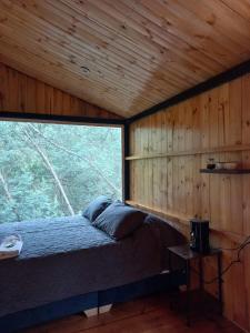 a bed in a room with a large window at Bosque Venado de Oro in Guatavita