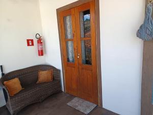 a living room with a couch and a wooden door at AP Temporada Monte Verde in Monte Verde