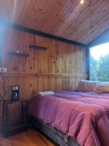 a bed in a room with a wooden wall at Bosque Venado de Oro in Guatavita