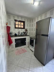 a kitchen with a stainless steel refrigerator and a window at Recanto da barra in Ilha do Bom Jardim