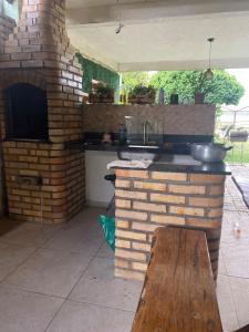 an outdoor kitchen with a brick oven and a wooden bench at Lagoa do Bonfim RN in Natal