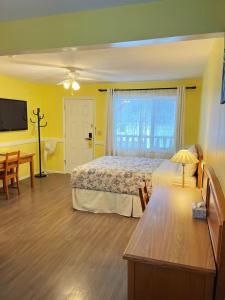 a bedroom with a bed and a table and a television at Rivermount Motel in Little Fort