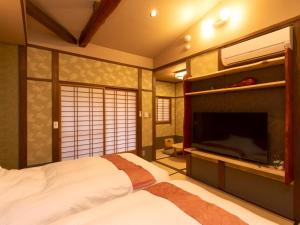 a bedroom with a bed and a flat screen tv at Wa no Yado Sagiritei in Yufu +39 photos
