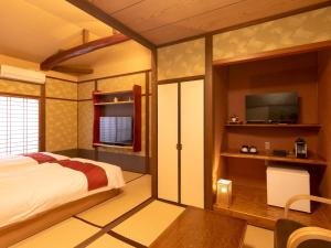 a bedroom with a bed and a flat screen tv at Wa no Yado Sagiritei in Yufu