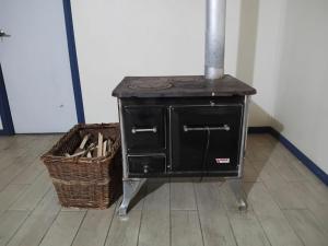 a black stove sitting in a room with a basket at Lomas de Hullinco Lodge in Petanesí Alto