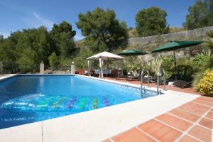 a swimming pool with chairs and umbrellas at Villa Quinto Pino in Frigiliana