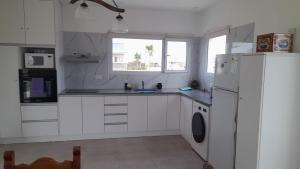 a kitchen with white cabinets and a white refrigerator at Ecos de mar in Mar del Sur +27 photos