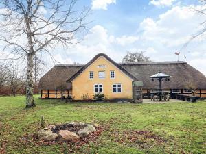 a large yellow house with a thatched roof at 4 person holiday home in Asaa in Aså