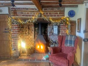 a living room with a brick fireplace with a red chair at Hill House in Colchester