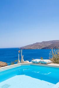a swimming pool with two swan statues in the water at Tholaria Boutique Hotel in Astypalaia Town