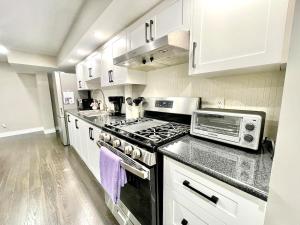 a kitchen with white cabinets and a stove top oven at Violet Escape Modern Apt 1B 1B, Kitchen, Parking in Richmond Hill +13 photos