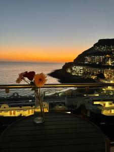a vase with flowers sitting on a table with the ocean at Vista Oceano Luxury Suite in Mogán