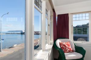 a chair on a balcony with a view of the water at Moana Lodge in Plimmerton