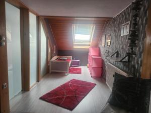 an attic room with a desk and a red rug at Ferienwohnung Silchmüller in Zella-Mehlis